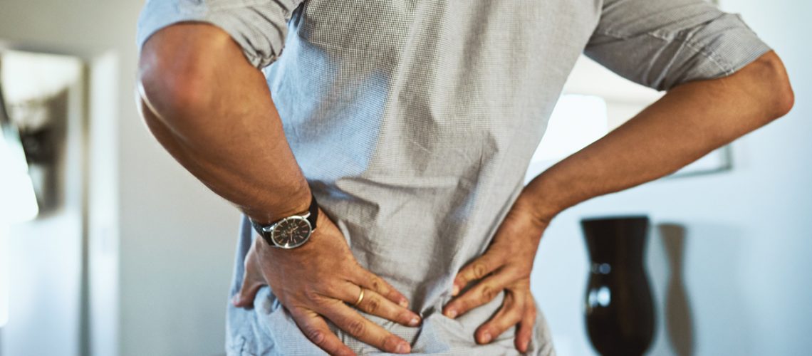 Rearview shot of an unrecognizable man holding his back in discomfort due to pain inside at home